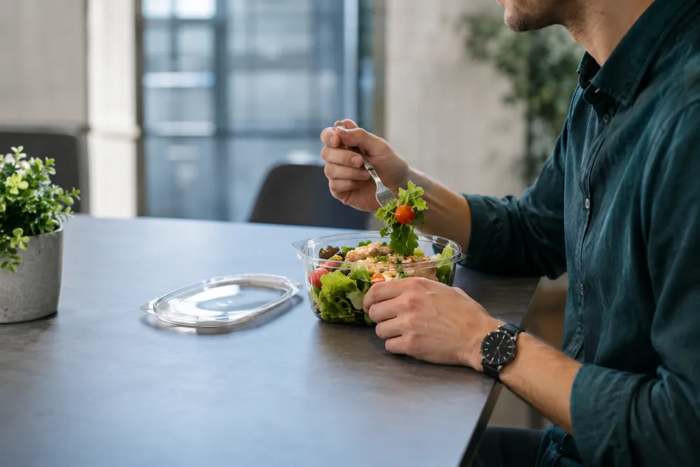 Medewerker eet een gezonde salade op het werk